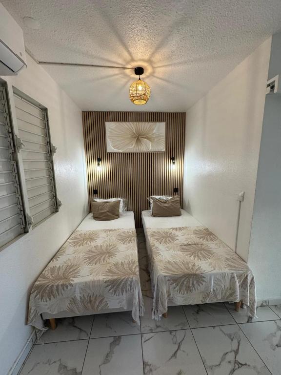 a room with two beds and a ceiling at Le Cocon Bleu in Le Moule