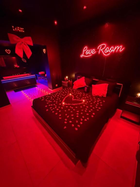 a red room with a bed with a love room sign at La nuit éternelle in Amilly