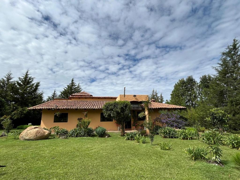 a house with a garden in front of it at Cabaña el nido del monte in Tapalpa