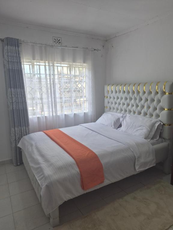 a bedroom with a large bed with a large window at Maroon House in Narok