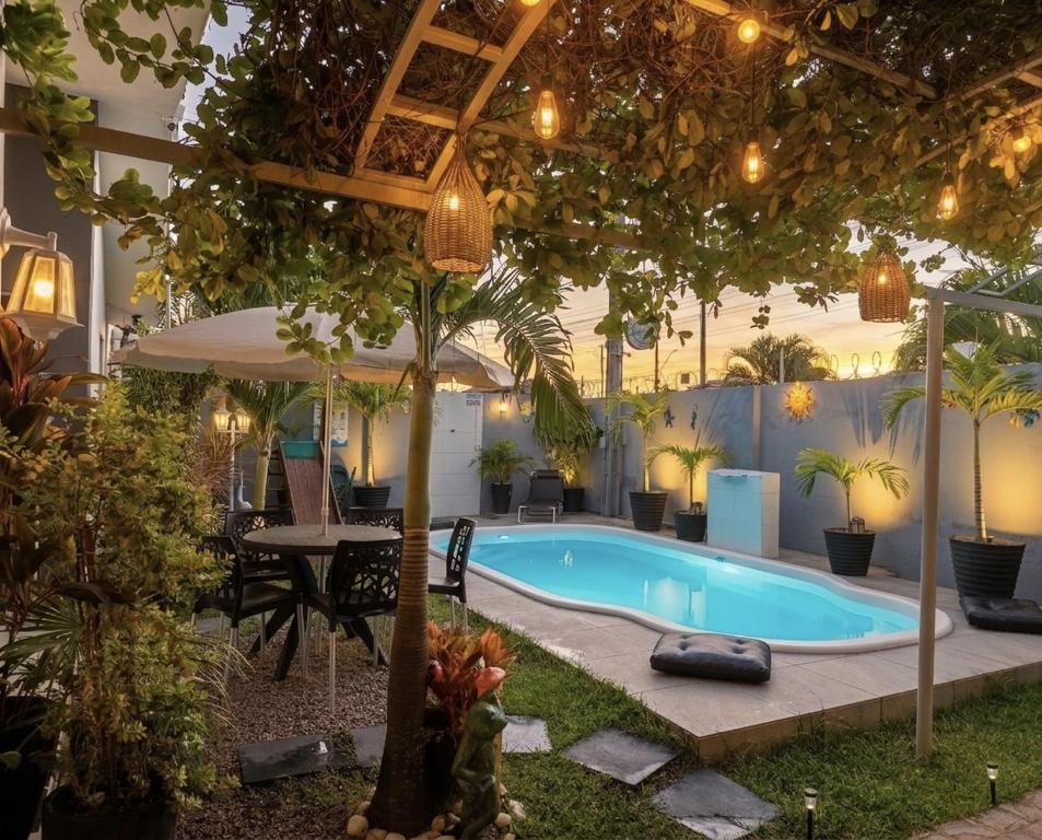 a swimming pool with a table and a tree at Garden JP in João Pessoa
