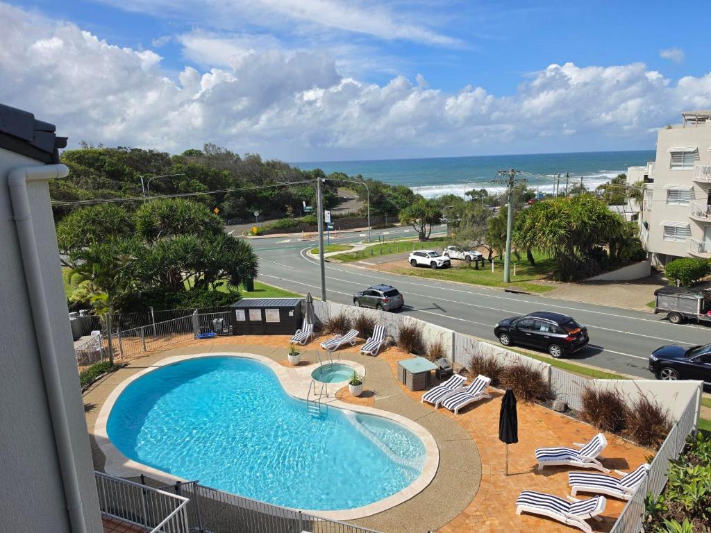 a swimming pool on a balcony with chairs and a road at Pandanus Coolum Beach in Coolum Beach