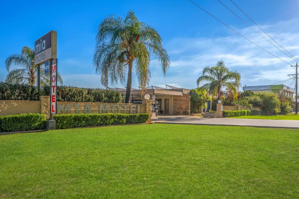a park with palm trees in front of a building at Mia Motel in Griffith