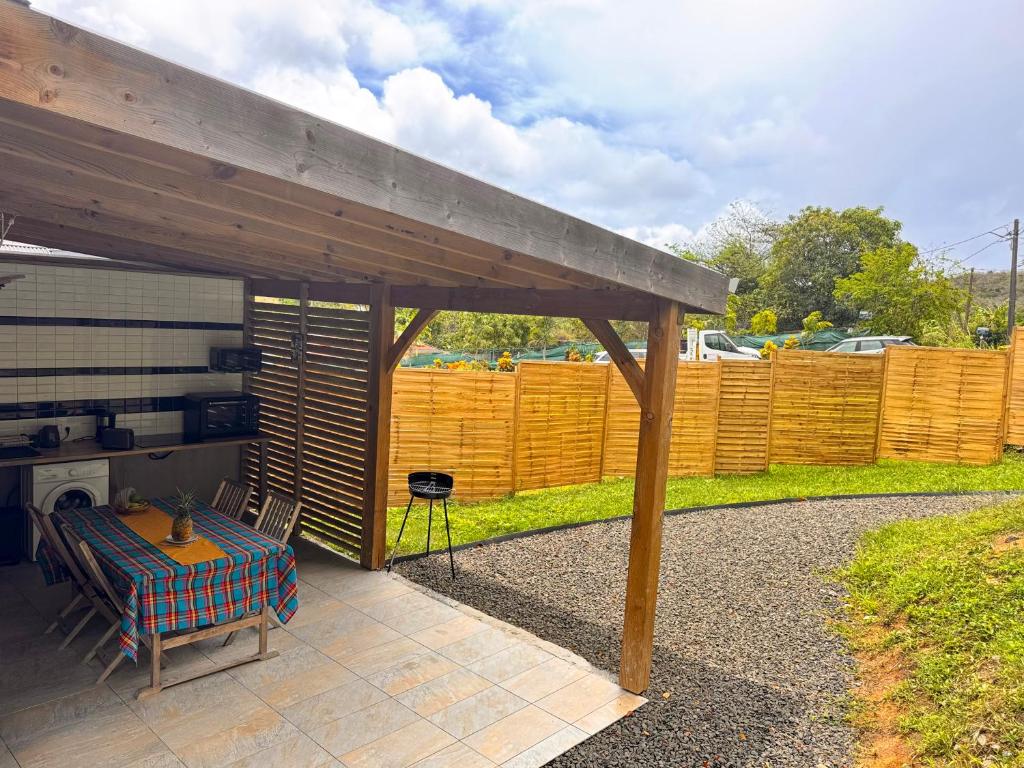 a covered patio with a table and a fence at Bungalow confortable et calme sud de la Martinique in Rivière-Salée