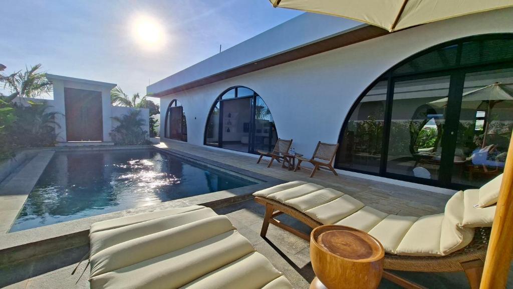 a house with a swimming pool with chairs and an umbrella at Casa Anagata Pandawa in Ungasan