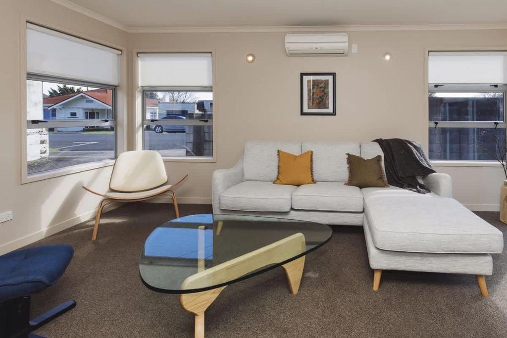 a living room with a couch and a glass table at Sail-Shaped Townhouse in New Plymouth in New Plymouth