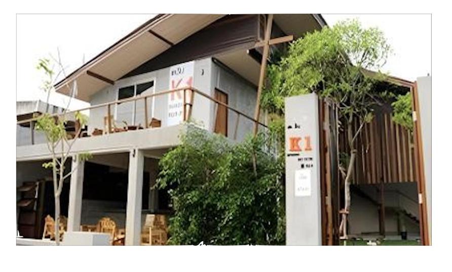 ein Gebäude, auf dessen Balkon Menschen sitzen in der Unterkunft K1 Hotel in Nan