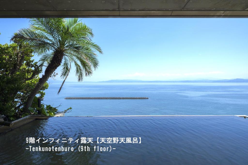 a view of the water with a palm tree at 夫婦露天風呂の宿吟松 in Ibusuki