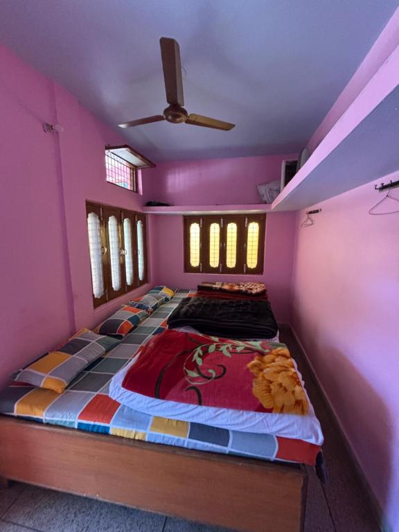 a large bed in a room with pink walls at Omji Ashram - Tapovan Kuti in Uttarkāshi