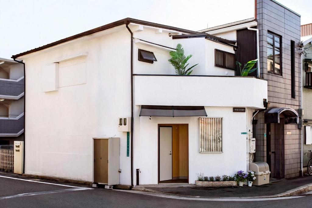 a white building with a door on a street at Lucky Today in Osaka