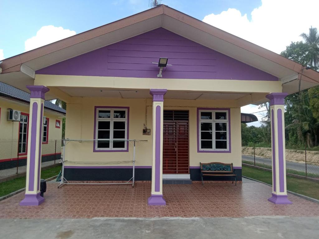 a purple and yellow house with a porch at Homestay Adilah A in Pasir Puteh