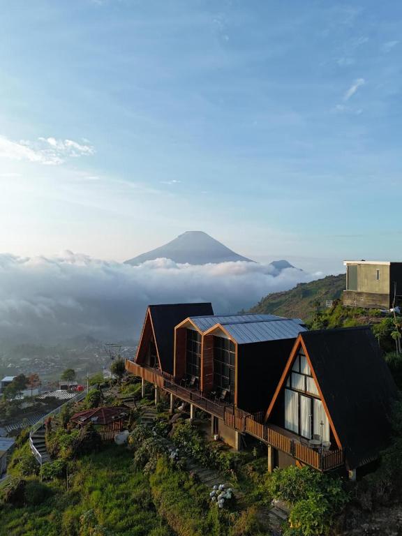 a house on a hill with a mountain in the background at Villa Dieng Sikapuk Hill Superior Cabin in Kejajar