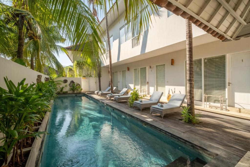 an indoor swimming pool with chairs and a house at Room & Vespa 4 - Central Seminyak Near Beach in Seminyak