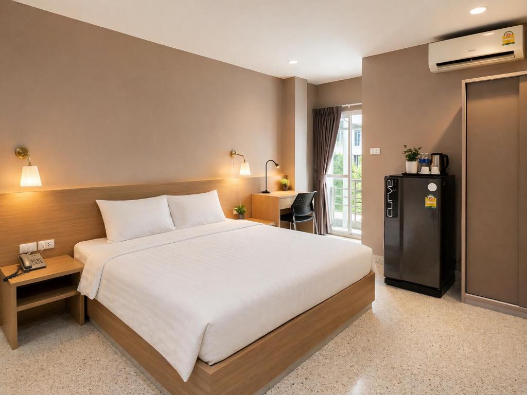 a bedroom with a large bed and a refrigerator at The Fifth Residence in Bangkok