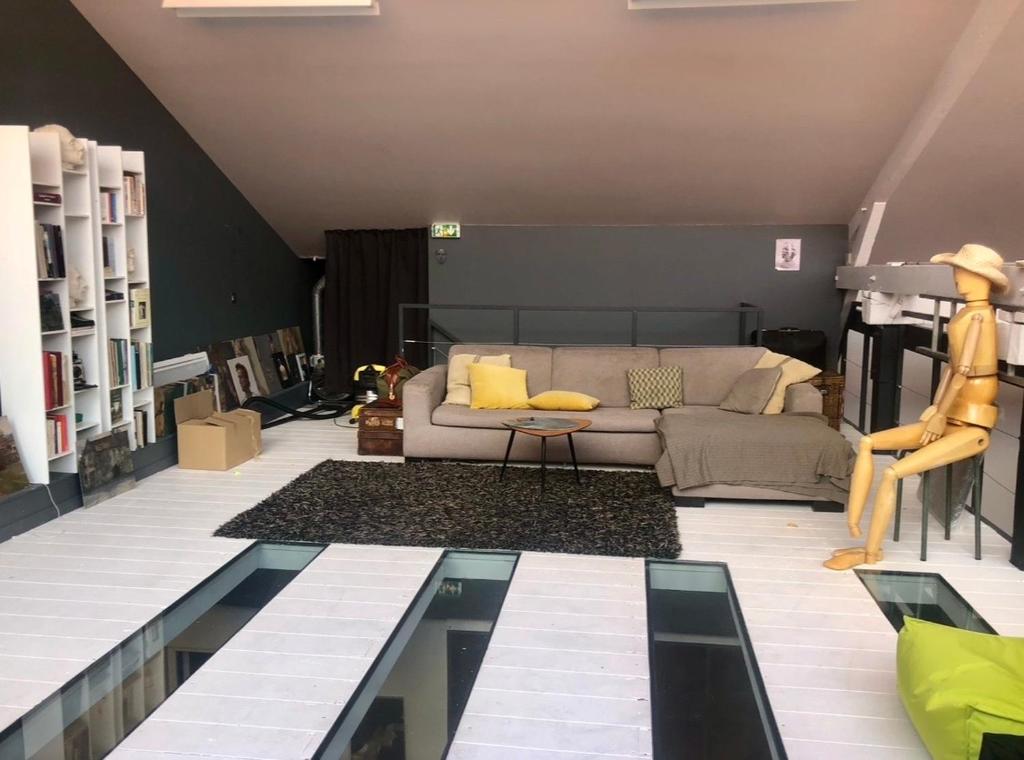 a living room with a couch and a glass table at Funky artists studio in Paris in Pantin