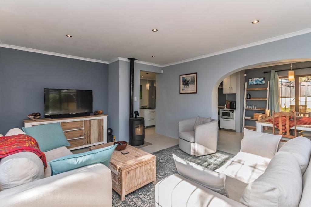 a living room with a white couch and a tv at Peaceful Lakeside Retreat Near Muizenberg in Lakeside