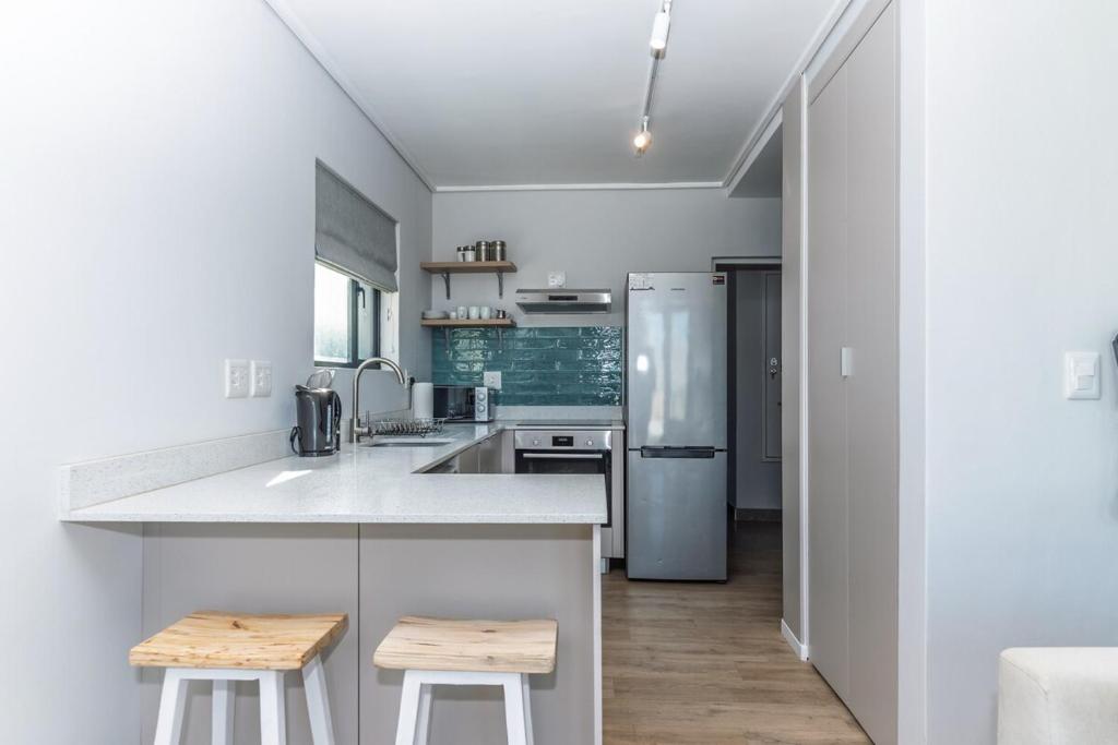 a kitchen with a counter and two stools at Stylish Studio with Ocean Views at Wavescapes in Muizenberg