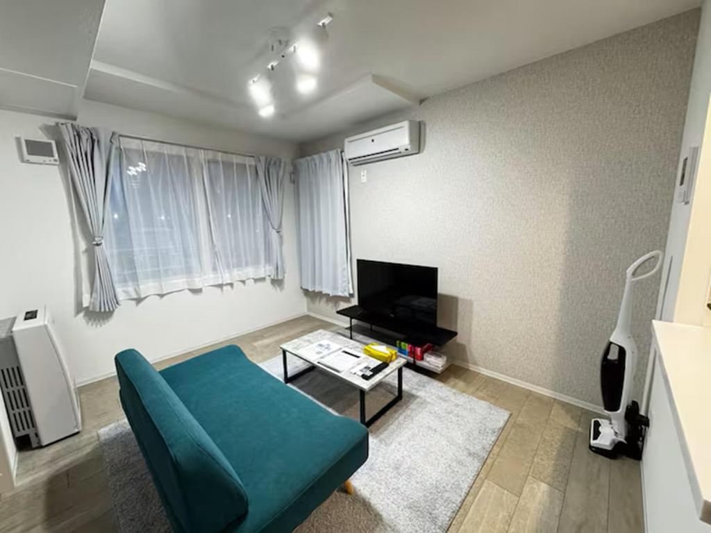 ein Wohnzimmer mit einer blauen Couch und einem Fernseher in der Unterkunft ハミルトンイースト in Sapporo