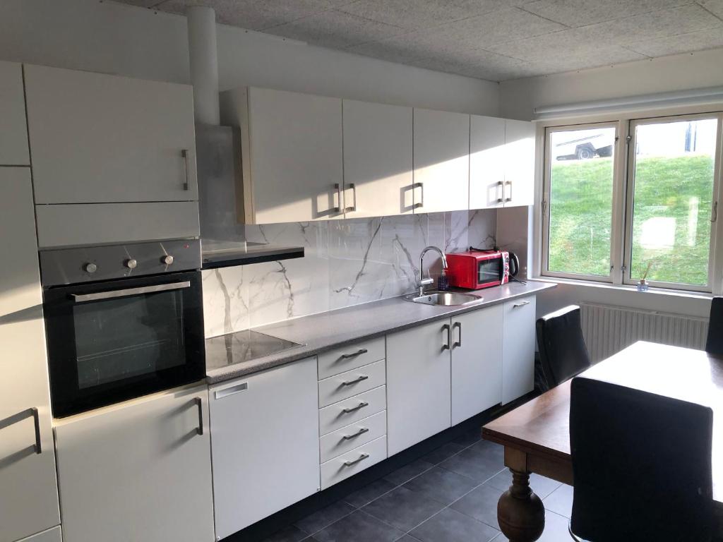 a kitchen with white cabinets and a table and a microwave at 2 soveværelse apartament in Præstø