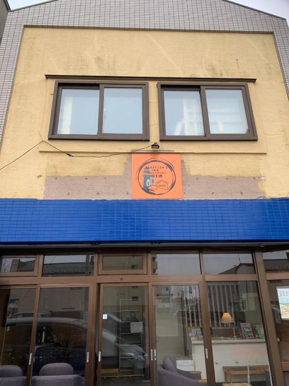 a building with three windows and a blue roof at 釧路の夕日に近い宿トラベラーズイン南大通 in Kushiro
