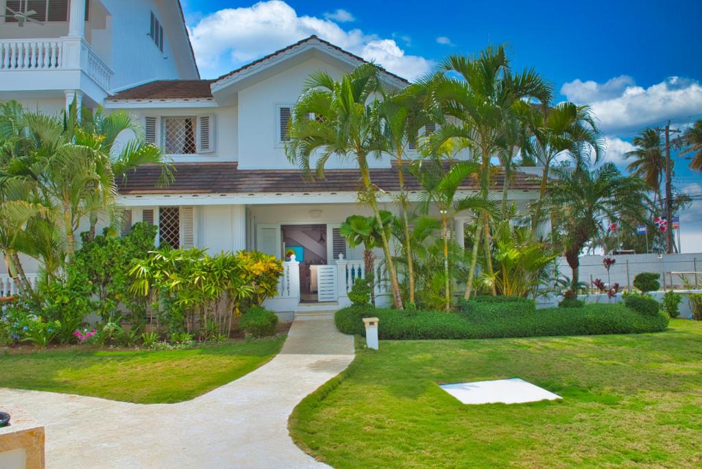 a white house with palm trees in the yard at Villa Chiara Beachfront Las Terrenas in El Limón