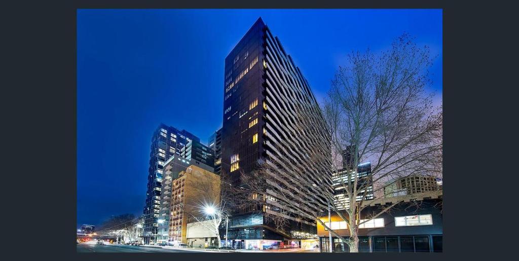 a tall building in a city at night at Aura on Flinders Serviced Apartments in Melbourne