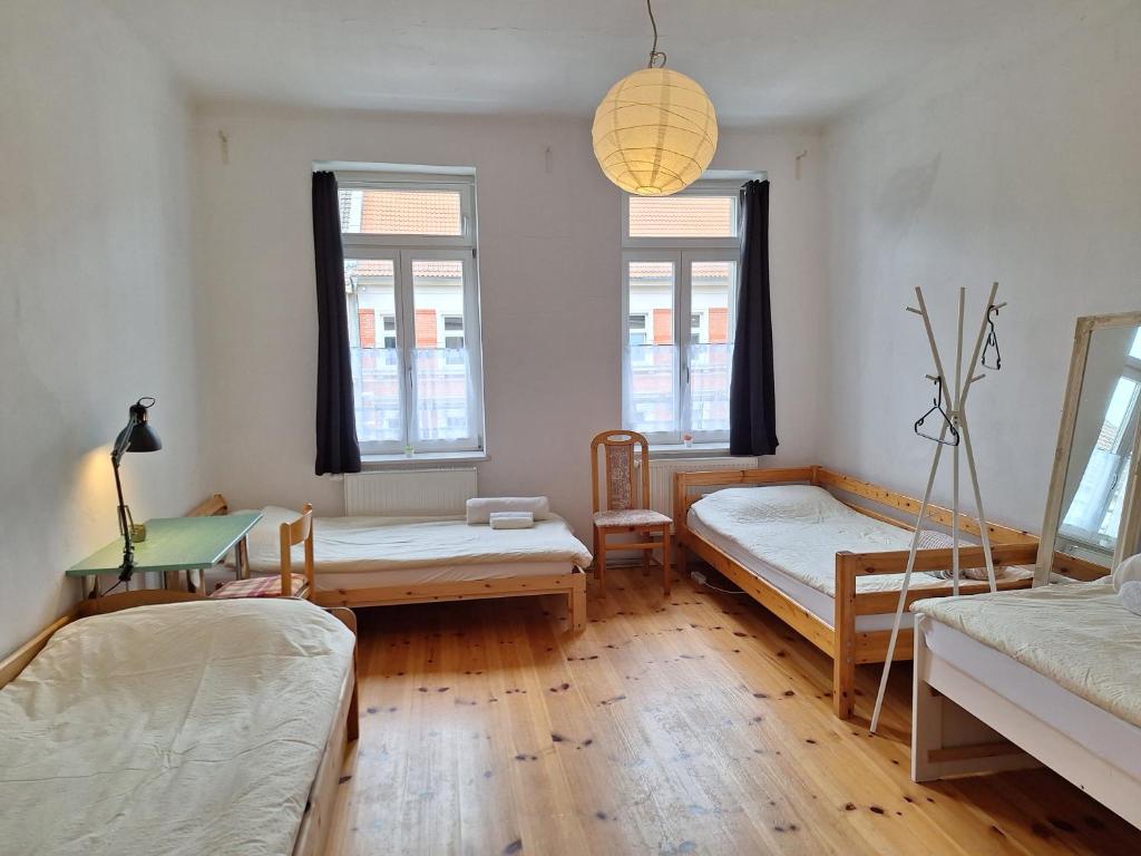 a room with two beds and a table and two windows at Helles geteiltes Mehrbettzimmer in Leipzig