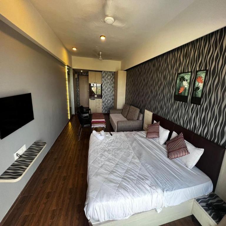 a bedroom with a large bed and a living room at Weekend address in Surat