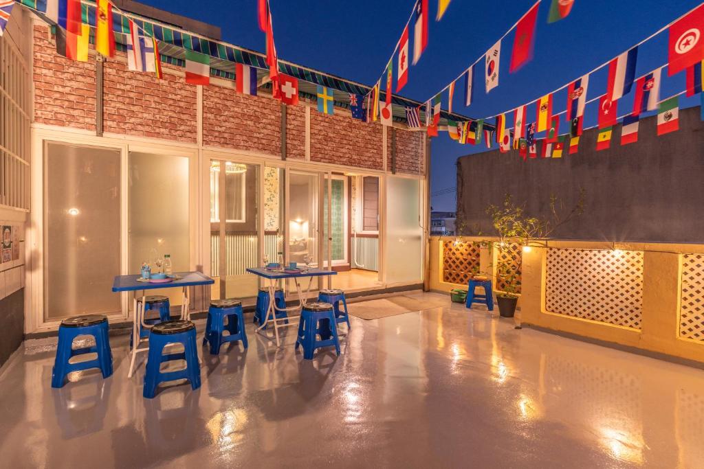 a patio with tables and blue chairs and flags at 행궁주택 in Samgong