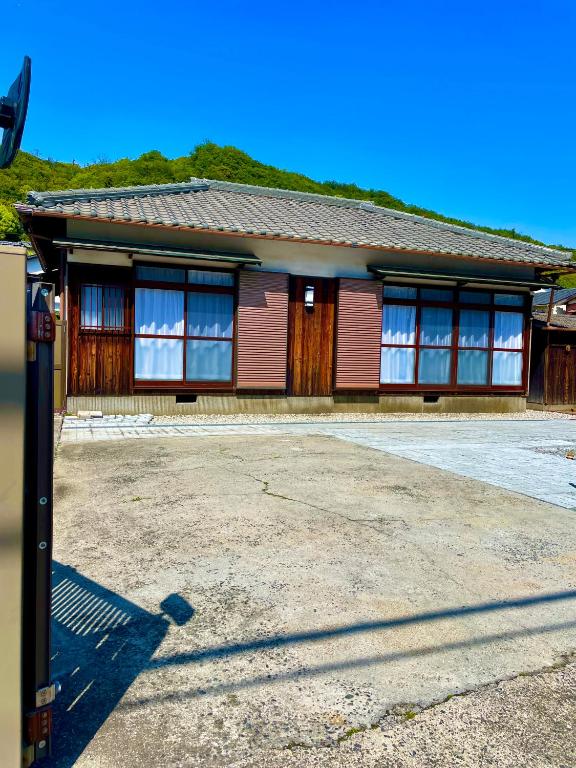 a red building with windows on a street at 古民家宿誠makoto in Tamano