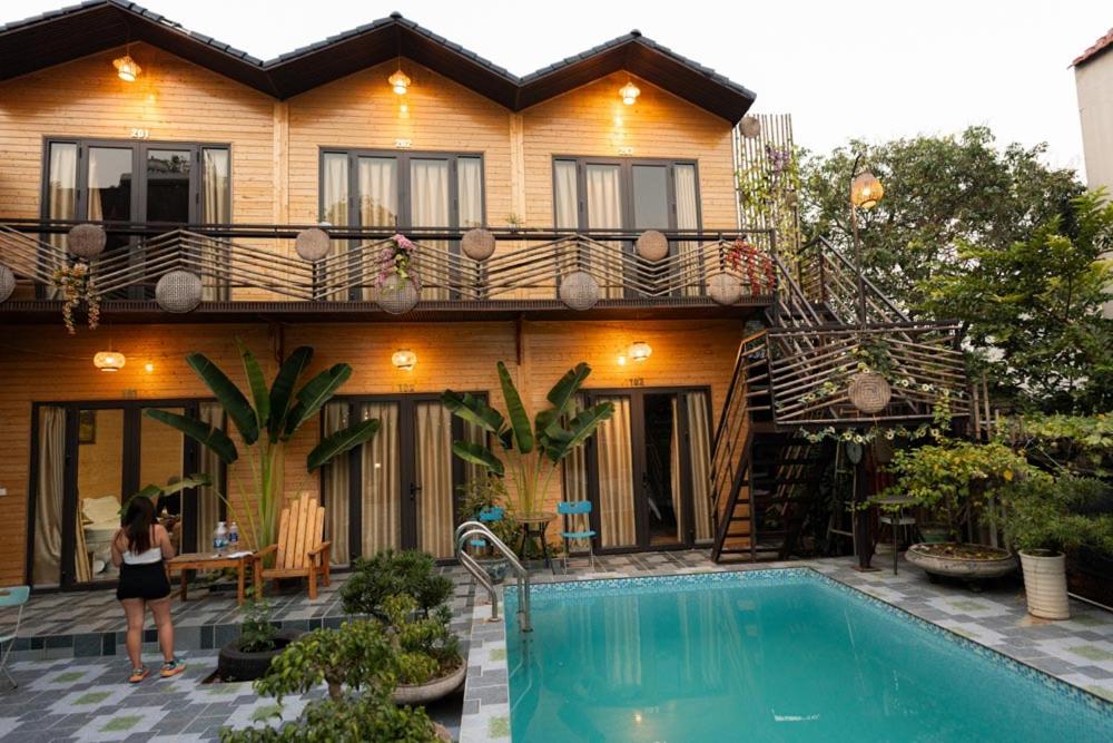 a woman standing in front of a house with a swimming pool at Tamcoc De Master Lux Bungalow in Ninh Binh