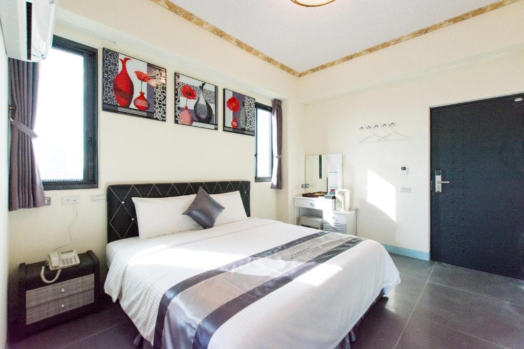 een slaapkamer met een groot wit bed en een aantal ramen bij Melinda Resort in Hengchun