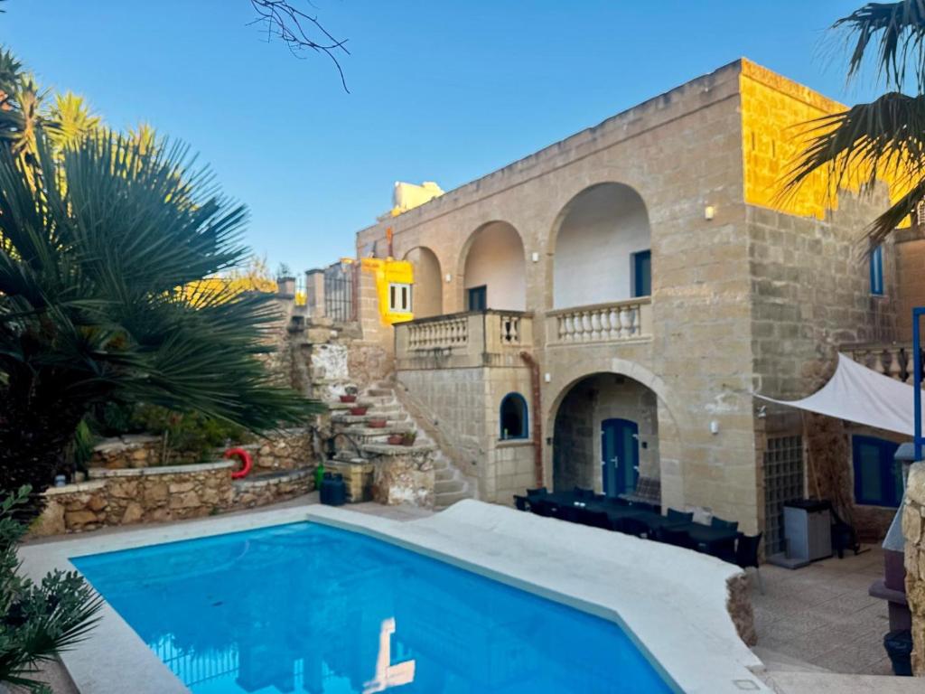 a house with a swimming pool in front of a building at Ta' Tereża Farmhouse in Xagħra