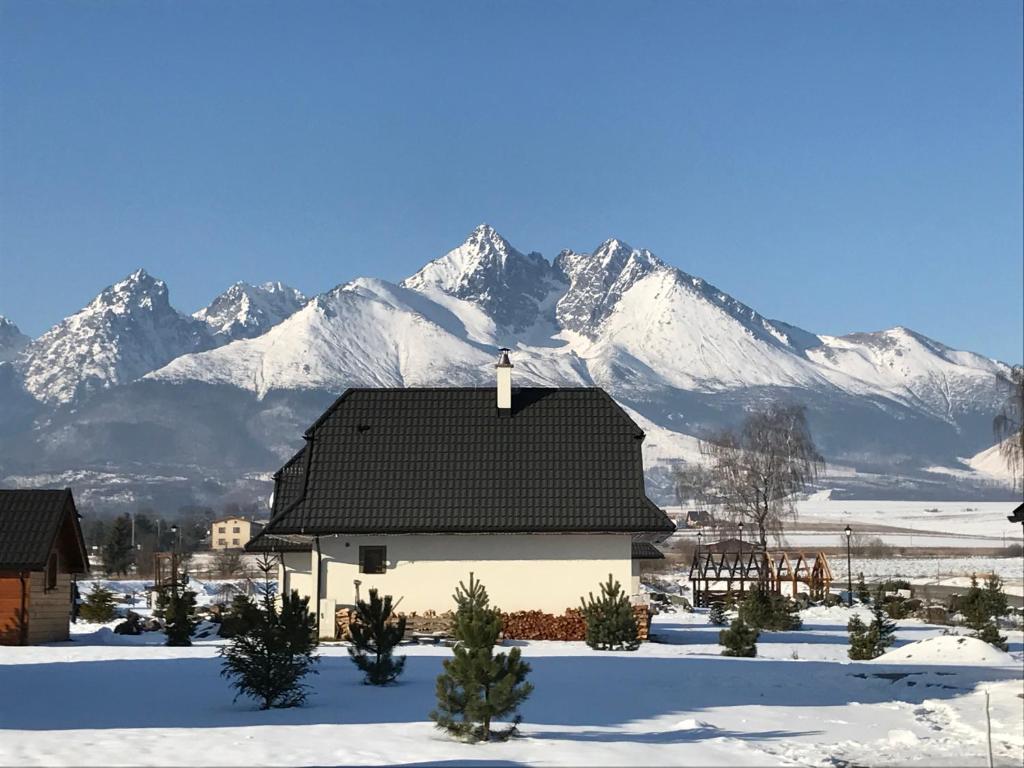 a house with snow covered mountains in the background at Villa Mia in Stará Lesná