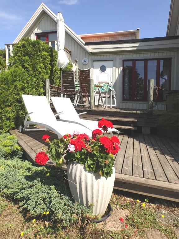 a group of white chairs on a deck with flowers at 1A, Stuga med 50m till strand in Byxelkrok