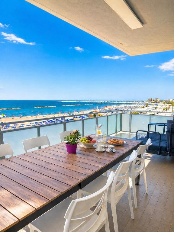 a wooden table and chairs on a balcony with the beach at Terrazzo Panoramico Fronte Mare Zamponi in Civitanova Marche