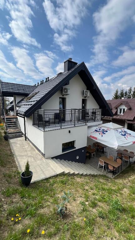 a house with a patio and two umbrellas on a deck at Pokoje nad Jeziorem Solina in Solina