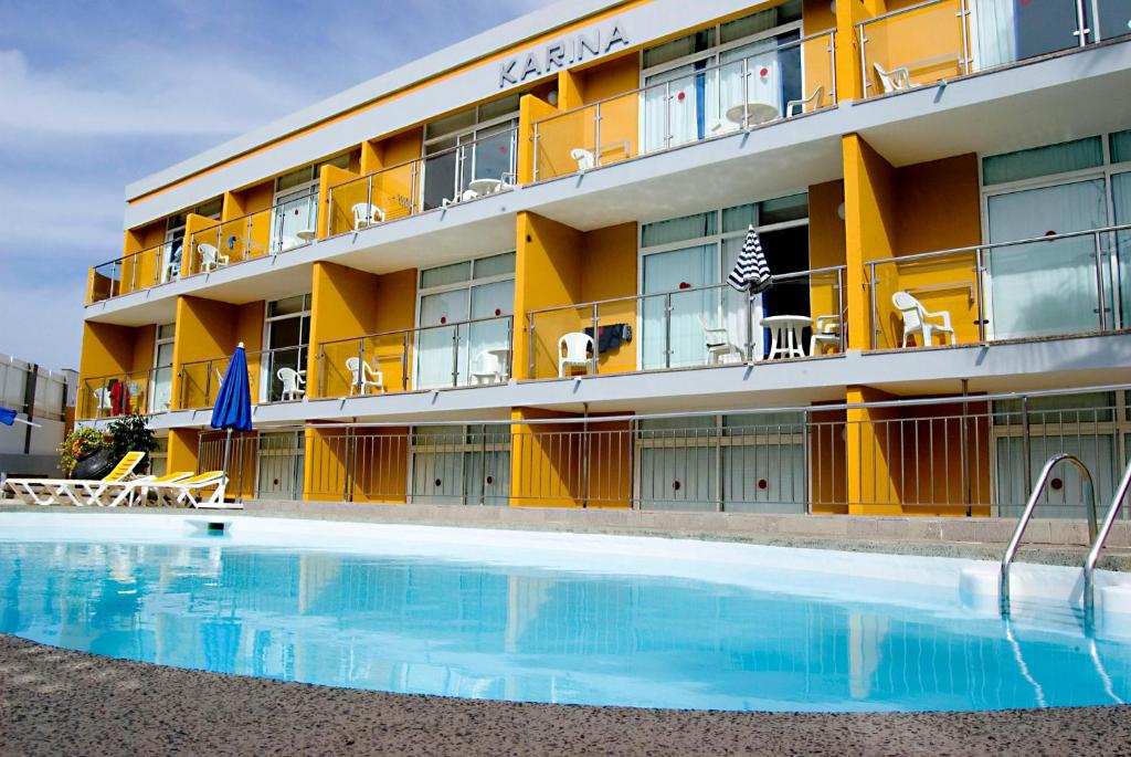 un hotel con piscina frente a un edificio en Apartamentos Karina en Playa del Ingles