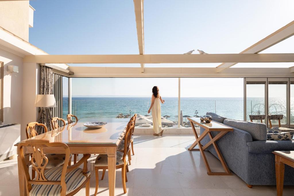 a woman standing in a living room looking out at the ocean at La Mer Escape in Nikiti