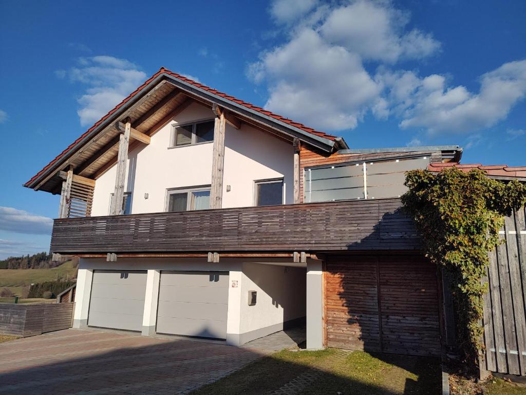 a white house with two garage doors and a fence at Ferienwohnung Landliebe in Reichertsried