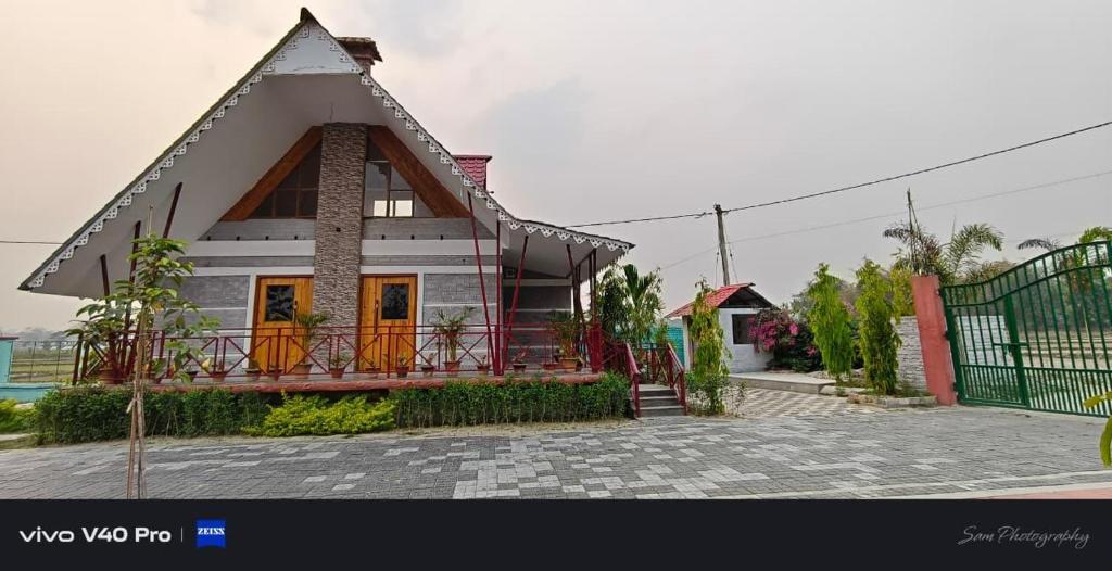 a house with a gambrel roof with a porch at Resort Bihanga in Chālsa Mahābāri