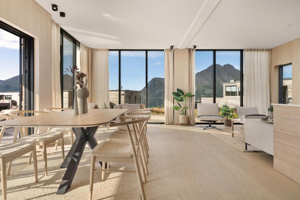 a dining room with a table and chairs and windows at Lyngvær Sunrise Lodge - Hot tub - No 11 in Storøya