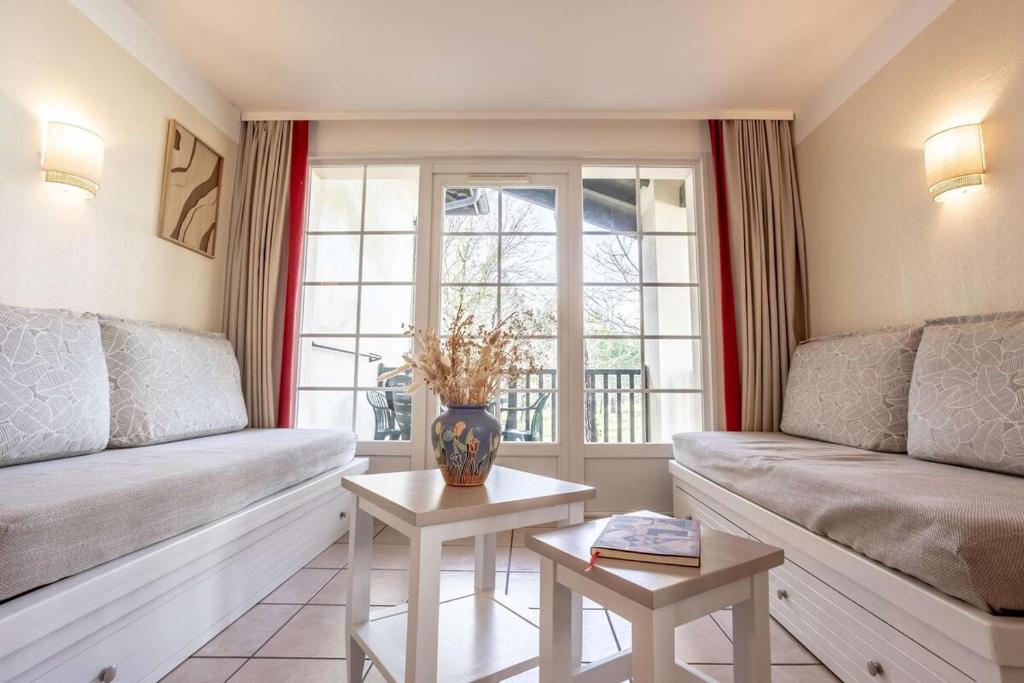 a living room with two couches and a window at L'Esquirou in Biscarrosse