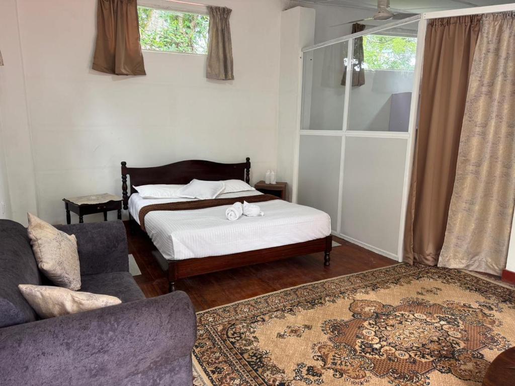 a living room with a bed and a couch at The Tamarind Villa in Kandy