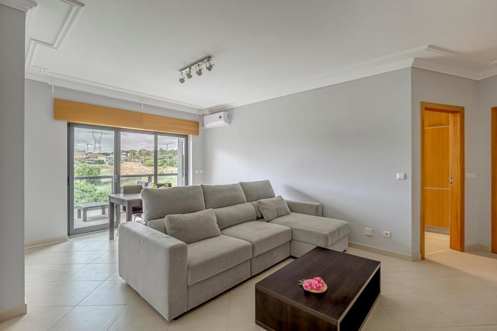 a living room with a couch and a table at 2-Bed Vialonga Vista Apartment in Lisbon