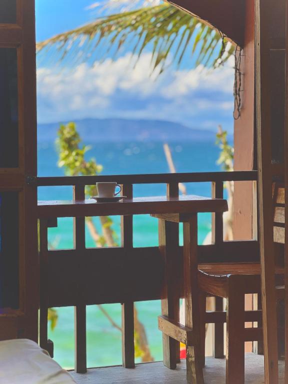 a table and chairs on a balcony with a view of the ocean at D Mountain Beach Resort - Beachfront in Puerto Galera