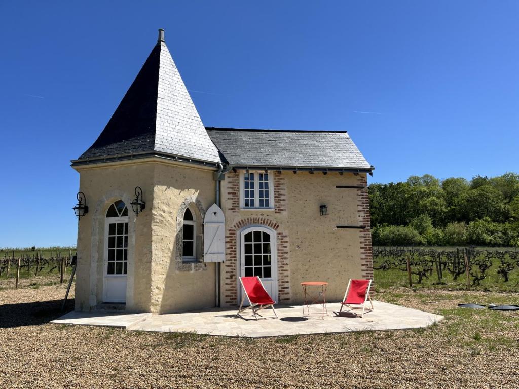 a building with two red chairs in front of it at Le Grand Clos Marçon in Marçon