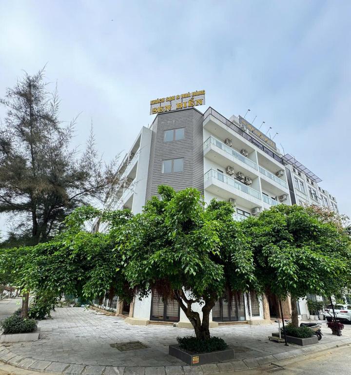 a large building with a tree in front of it at Sen Biển Hotel Luxury Sầm Sơn in Sầm Sơn