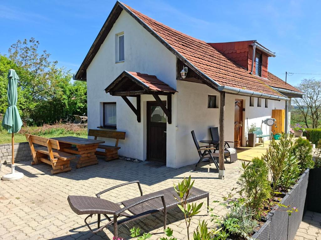 a small white house with a picnic table and chairs at Ferienhaus Weingarten Eisenberg in Vaskeresztes