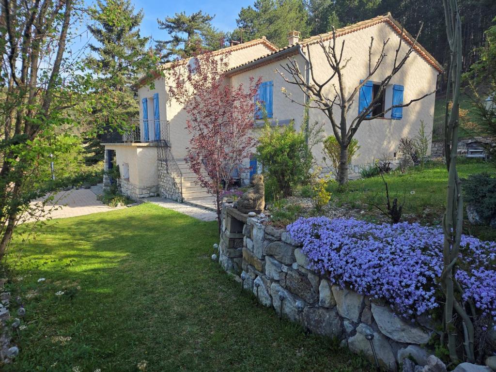 a house with a stone retaining wall and purple flowers at Aurelia Verdon in Angles